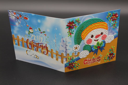 Mr. Snowman is Sitting Under a Beautiful Green, Fancy Decorated Christmas Tree and Red Poinsettias. Card has Crystals and Gemstones.