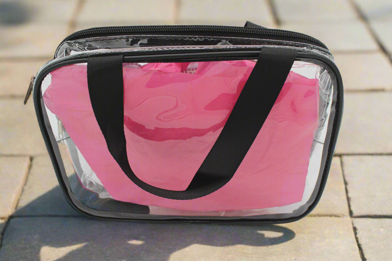 Clear plastic bag with black handle containing pink items on a white background