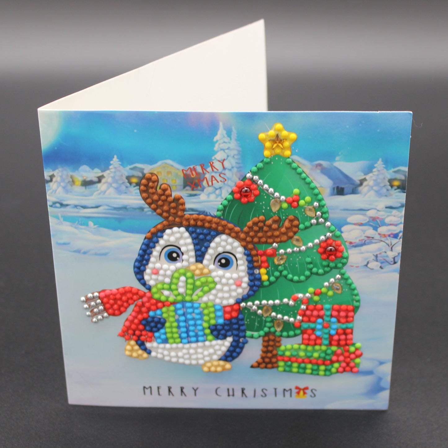 Greeting Card with a Cute Little Penguin with a Red Scarf, Christmas Tree and Gifts. Card has Crystals and Gemstones.