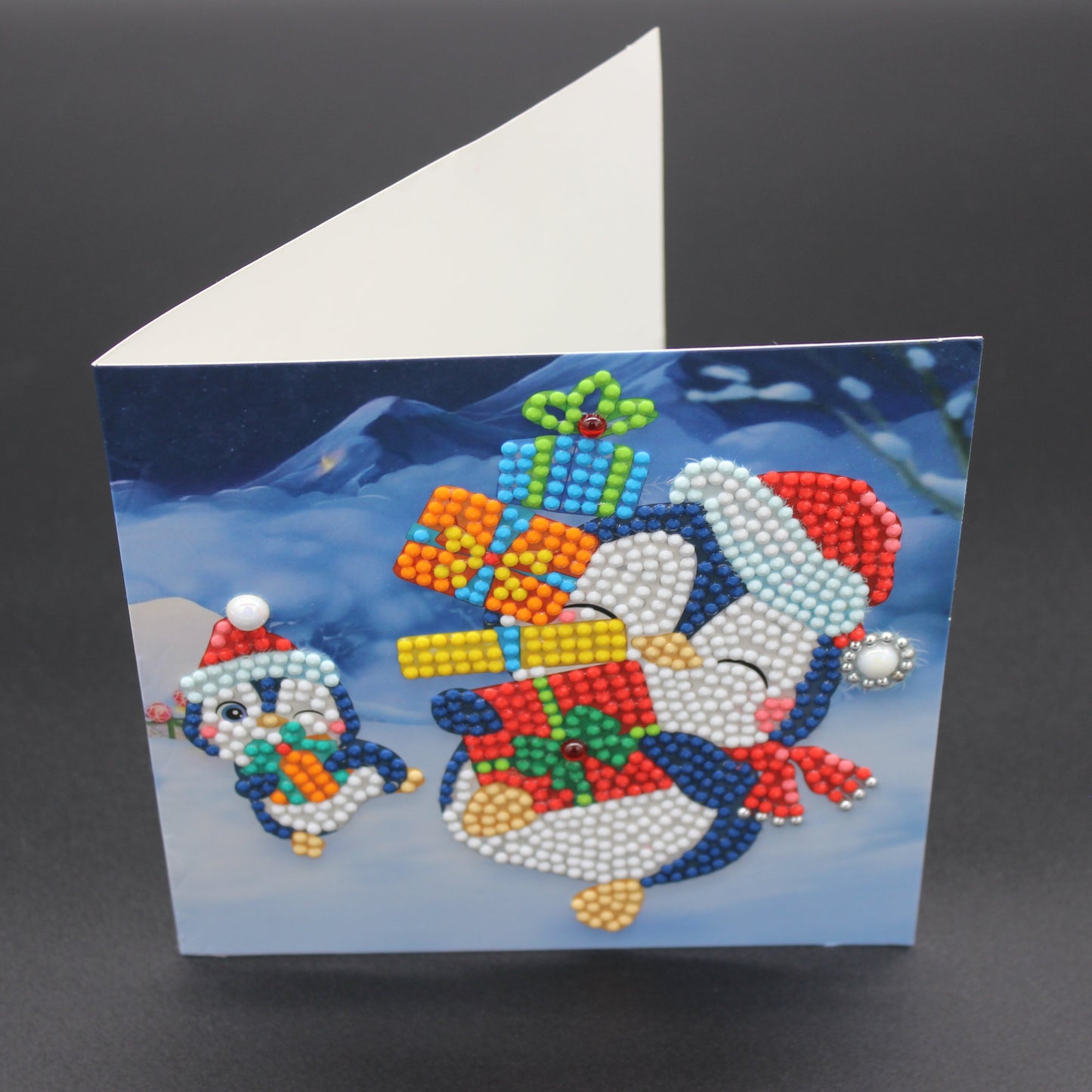 Two Cute Little Penguins Ice Skating with Presents.  Card has Crystals and Gemstones.