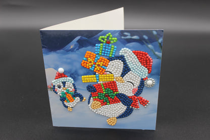 Two Cute Little Penguins Ice Skating with Presents.  Card has Crystals and Gemstones.