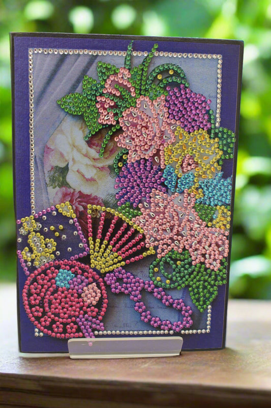 Decorative card with beadwork featuring a floral design on a purple background.
