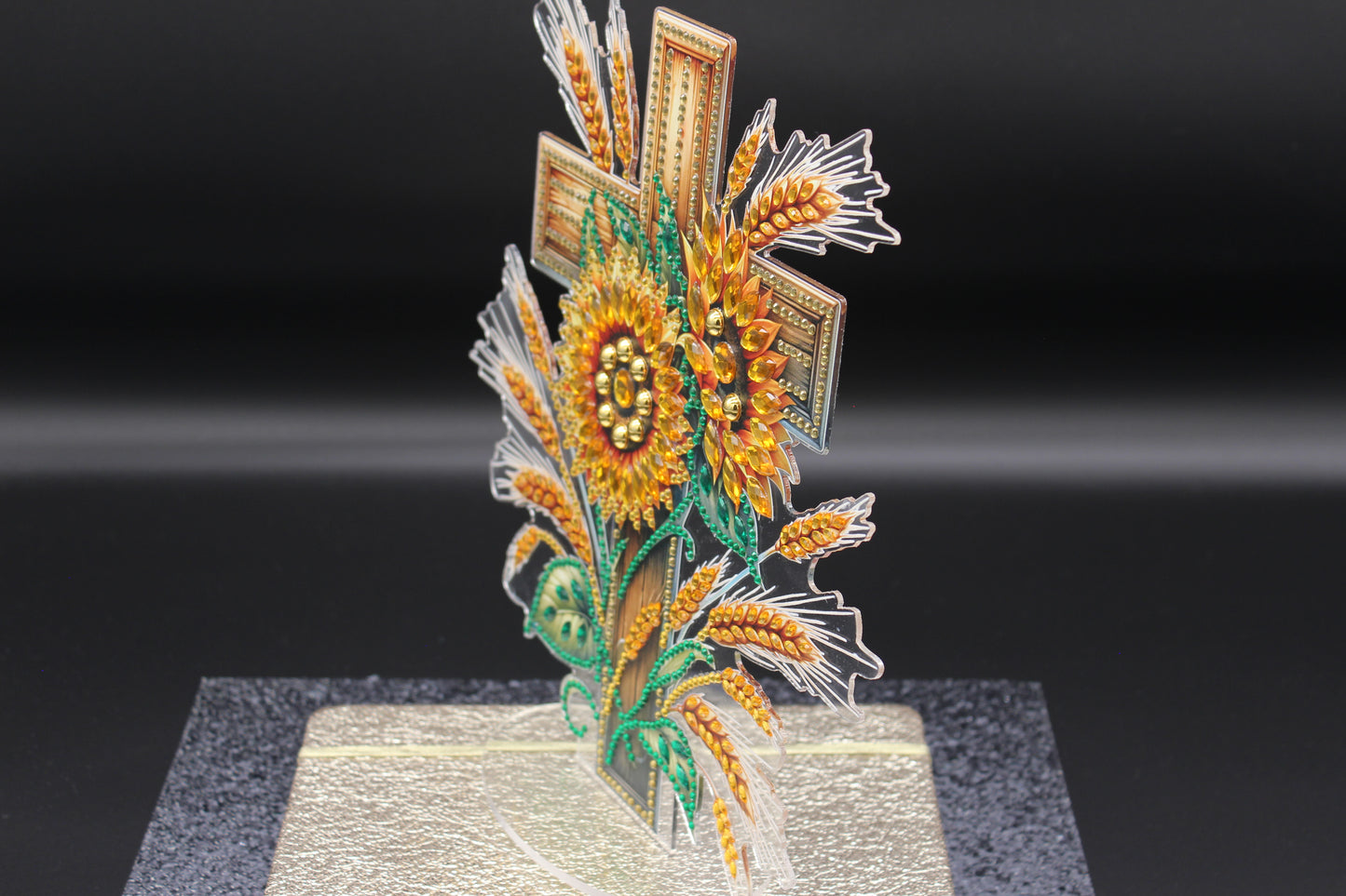 Decorative sunflower and wheat design on a stand against a black background