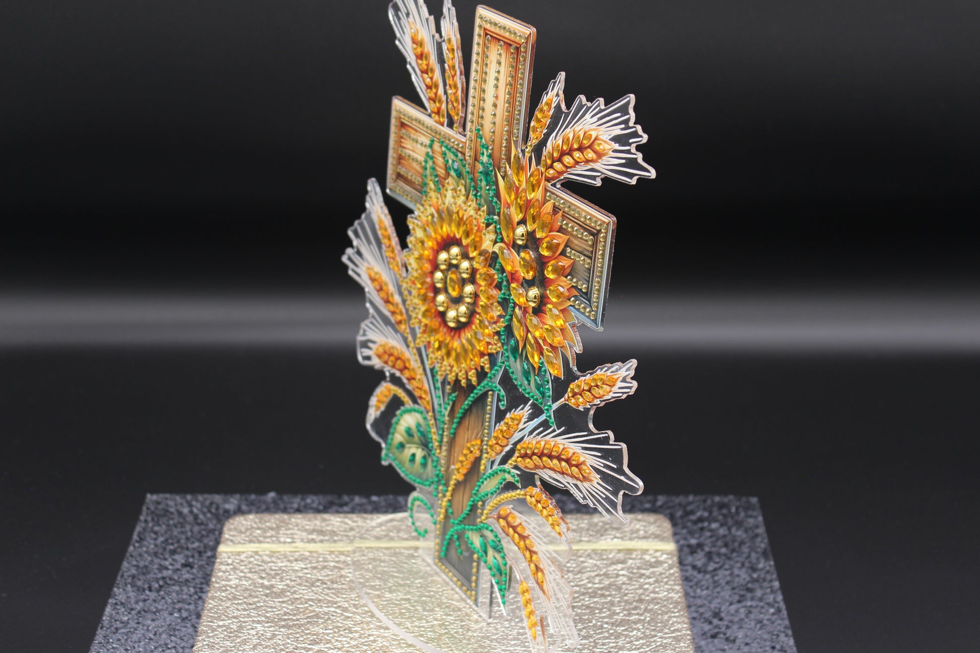 Decorative sunflower and wheat design on a stand against a black background