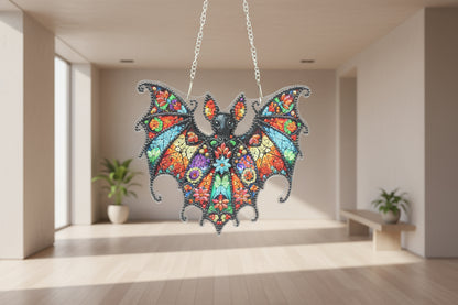 Colorful bat-shaped pendant with floral patterns on a dark background
