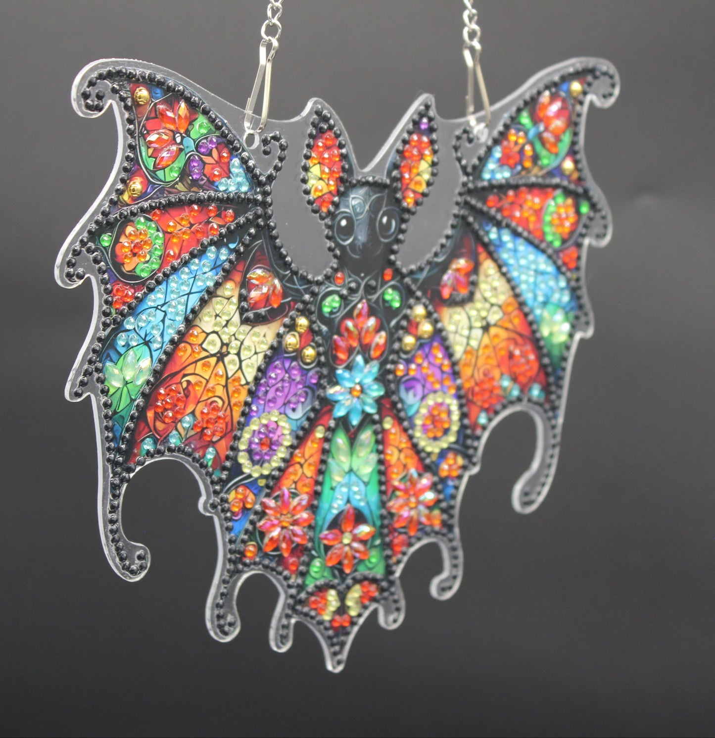 Colorful bat-shaped pendant on a dark background