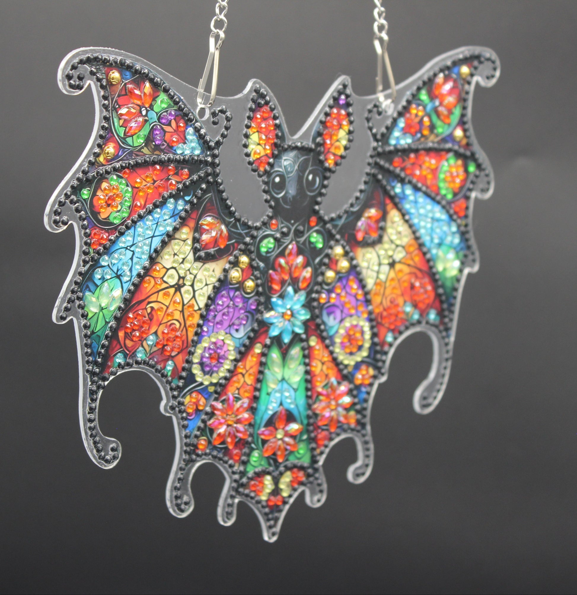 Colorful bat-shaped pendant on a dark background