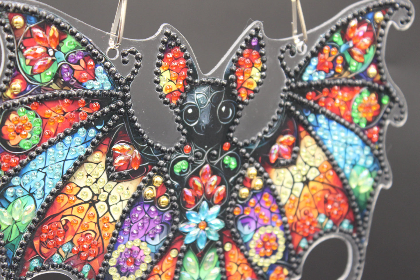 Colorful bat-shaped pendant with intricate designs on a dark background