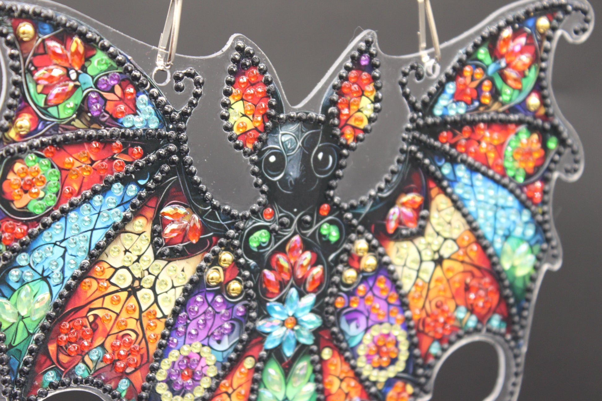 Colorful bat-shaped pendant with intricate designs on a dark background