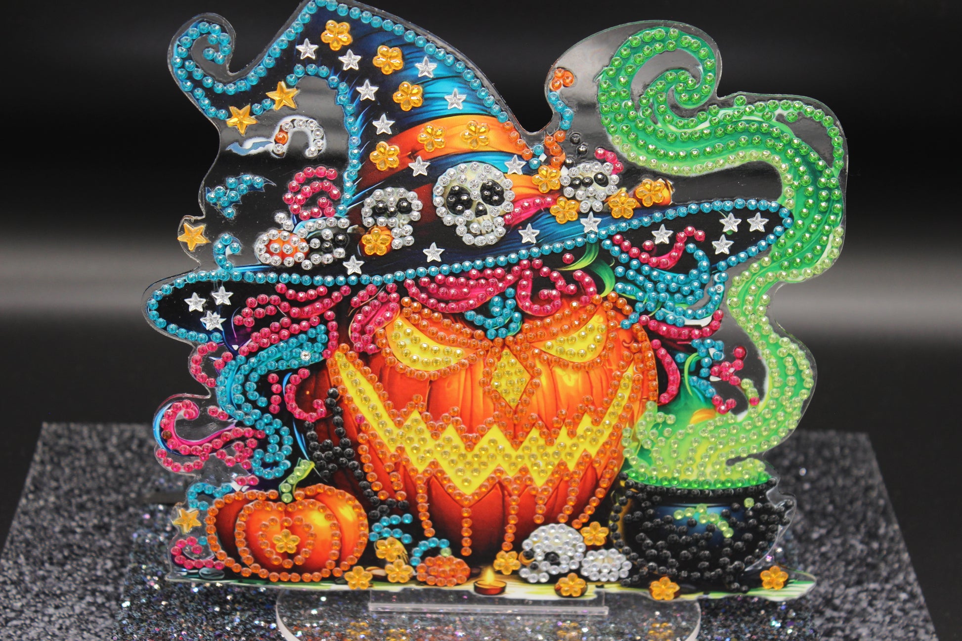 Decorative Halloween-themed craft with colorful beads and pumpkins on a black background