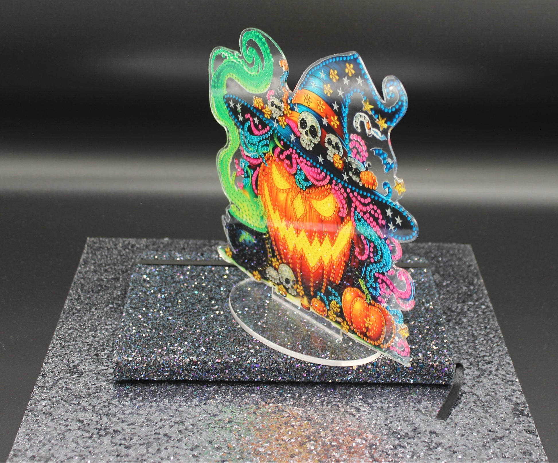 Colorful Halloween-themed decorative item on a black stand with a dark background