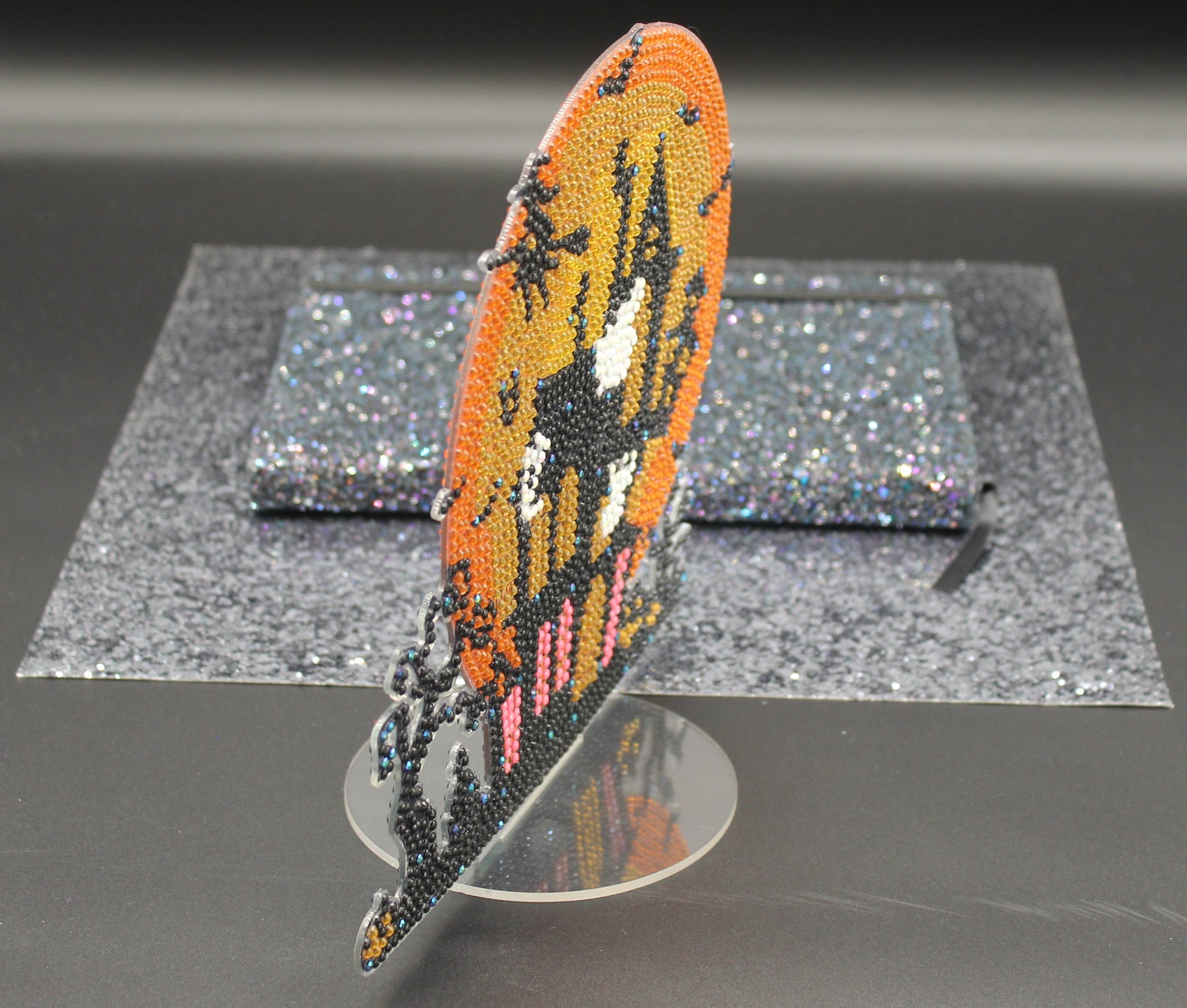 Decorative feather with beadwork on a stand against a dark background