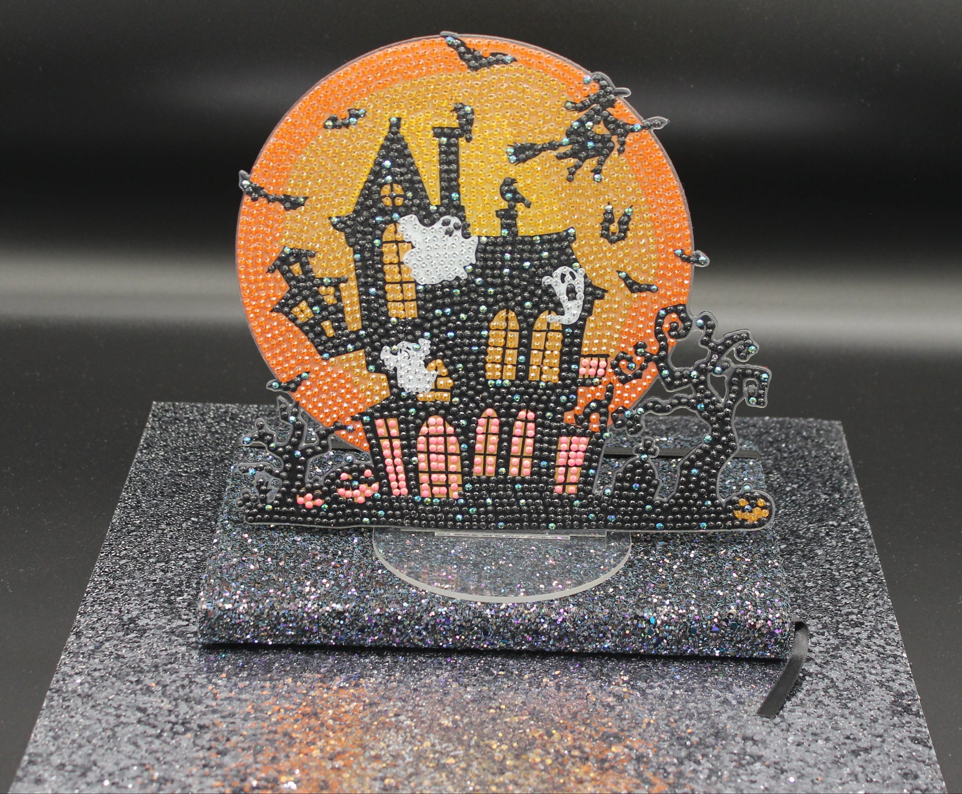 Halloween-themed decorative item with a castle design on a black stand against a dark background