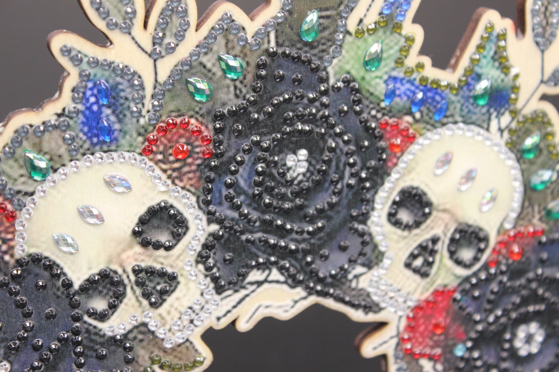 Decorative item with skulls and floral patterns embellished with rhinestones on a dark background