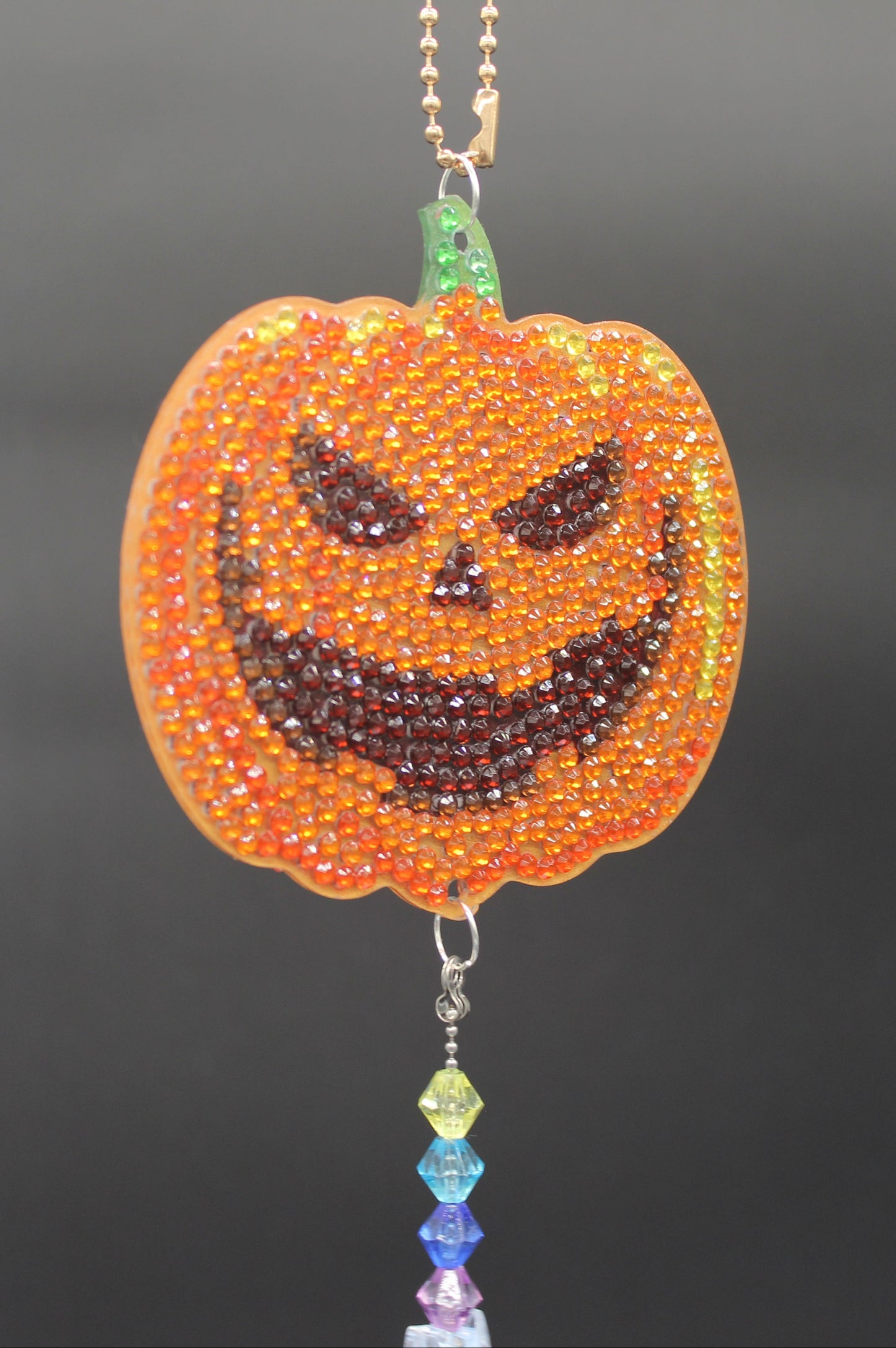 Halloween-themed beaded decorations including a pumpkin, ghost, and witch on a dark background.