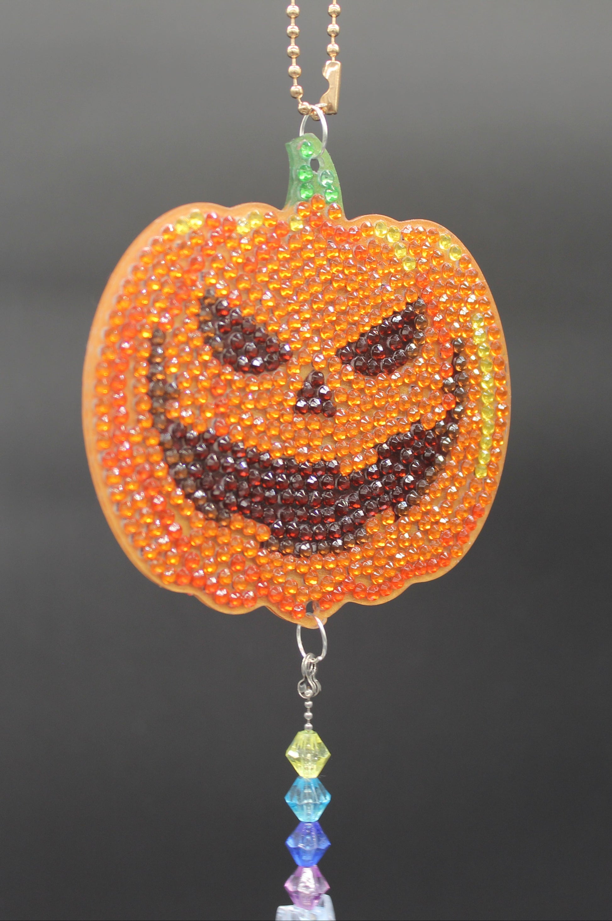 Halloween-themed beaded decorations including a pumpkin, ghost, and witch on a dark background.