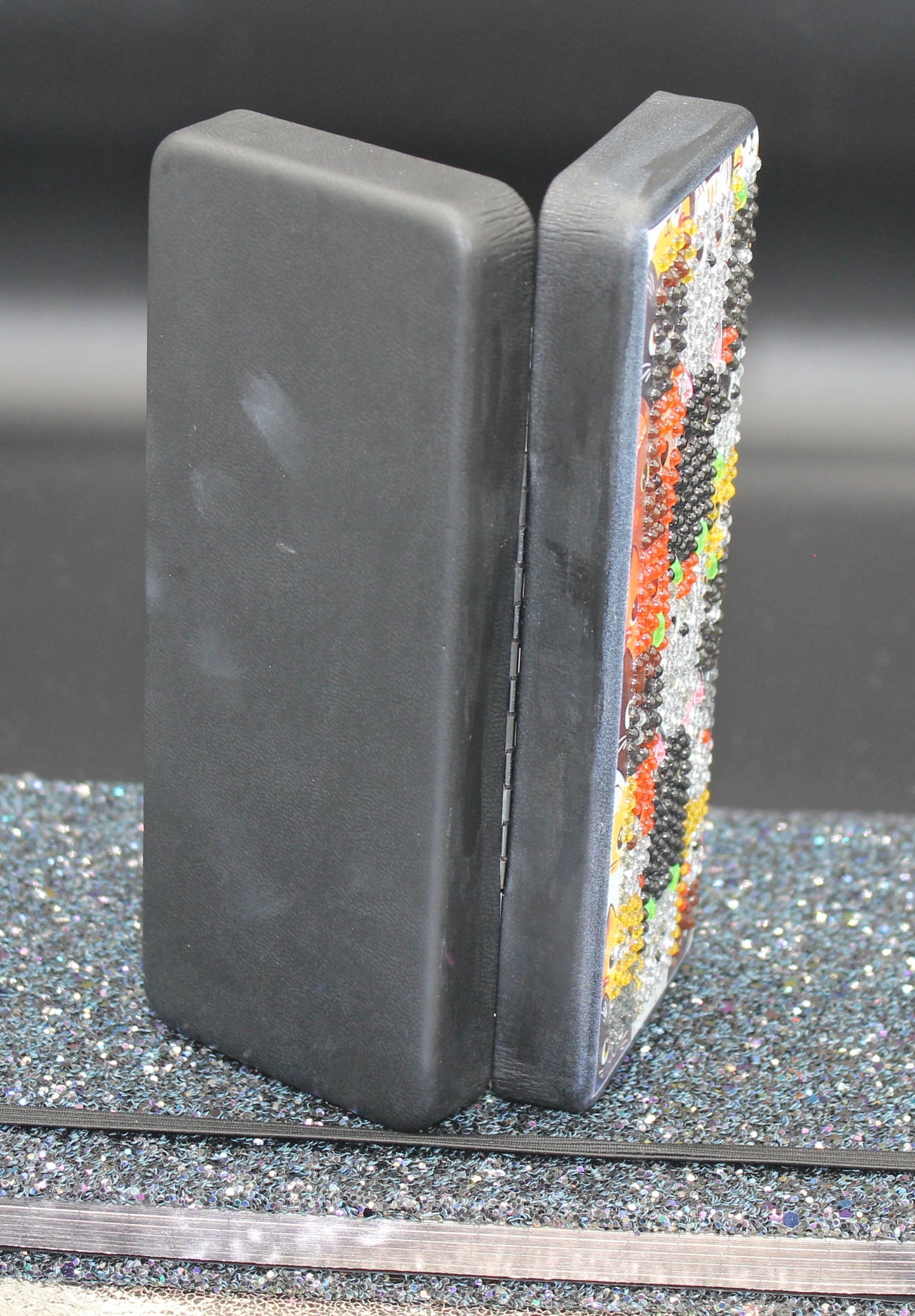 Two bookends with one featuring a colorful mosaic design on a gray surface.