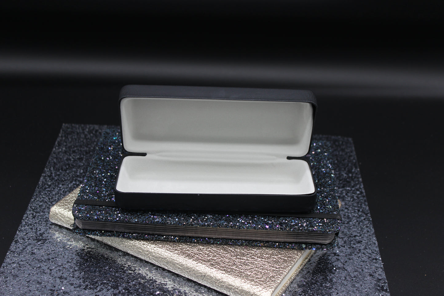 Open black case with gray interior on a textured black surface