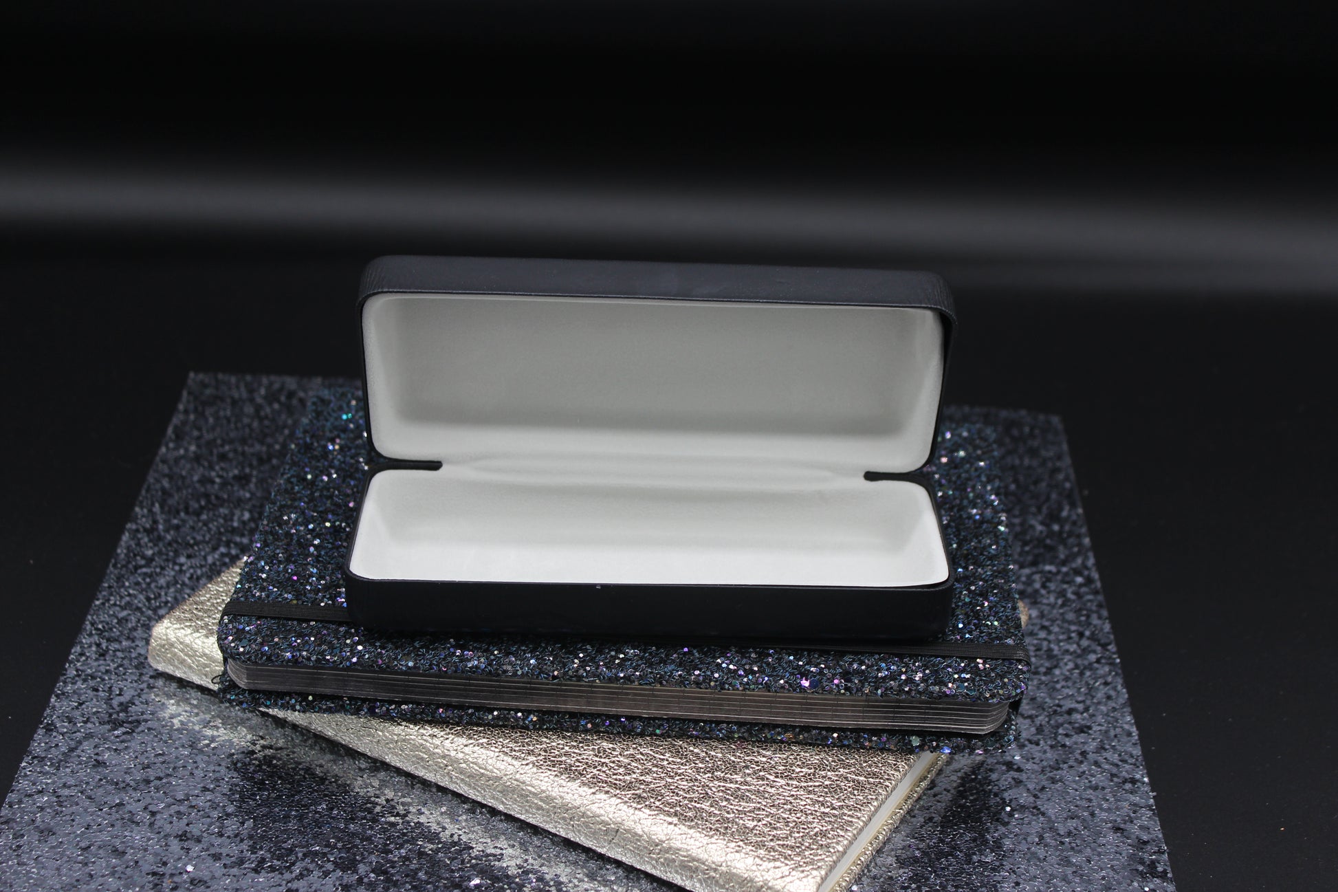 Open black case with gray interior on a textured black surface