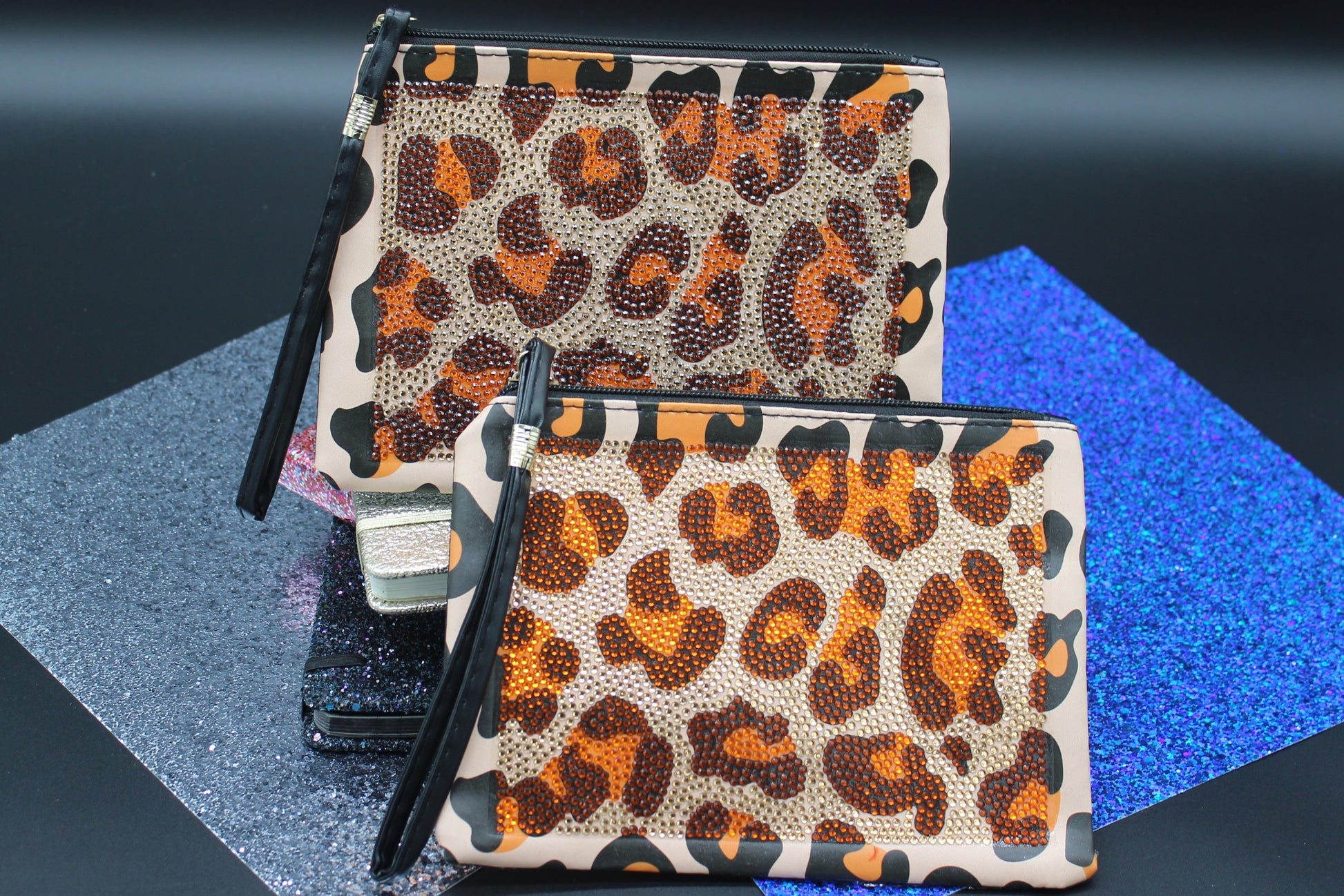 Two leopard print pouches on a reflective surface with a dark background
