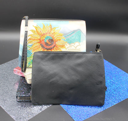 Black pouch on a gray surface with a colorful notebook and sunflower design.