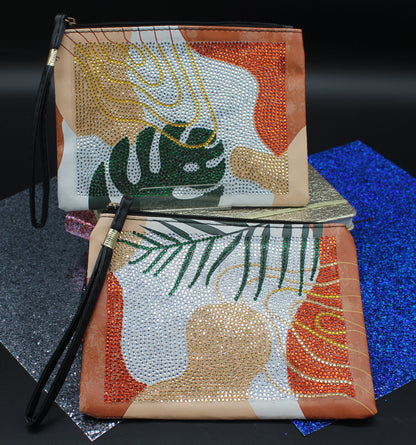 Two beaded clutch bags with leaf patterns on a dark surface.