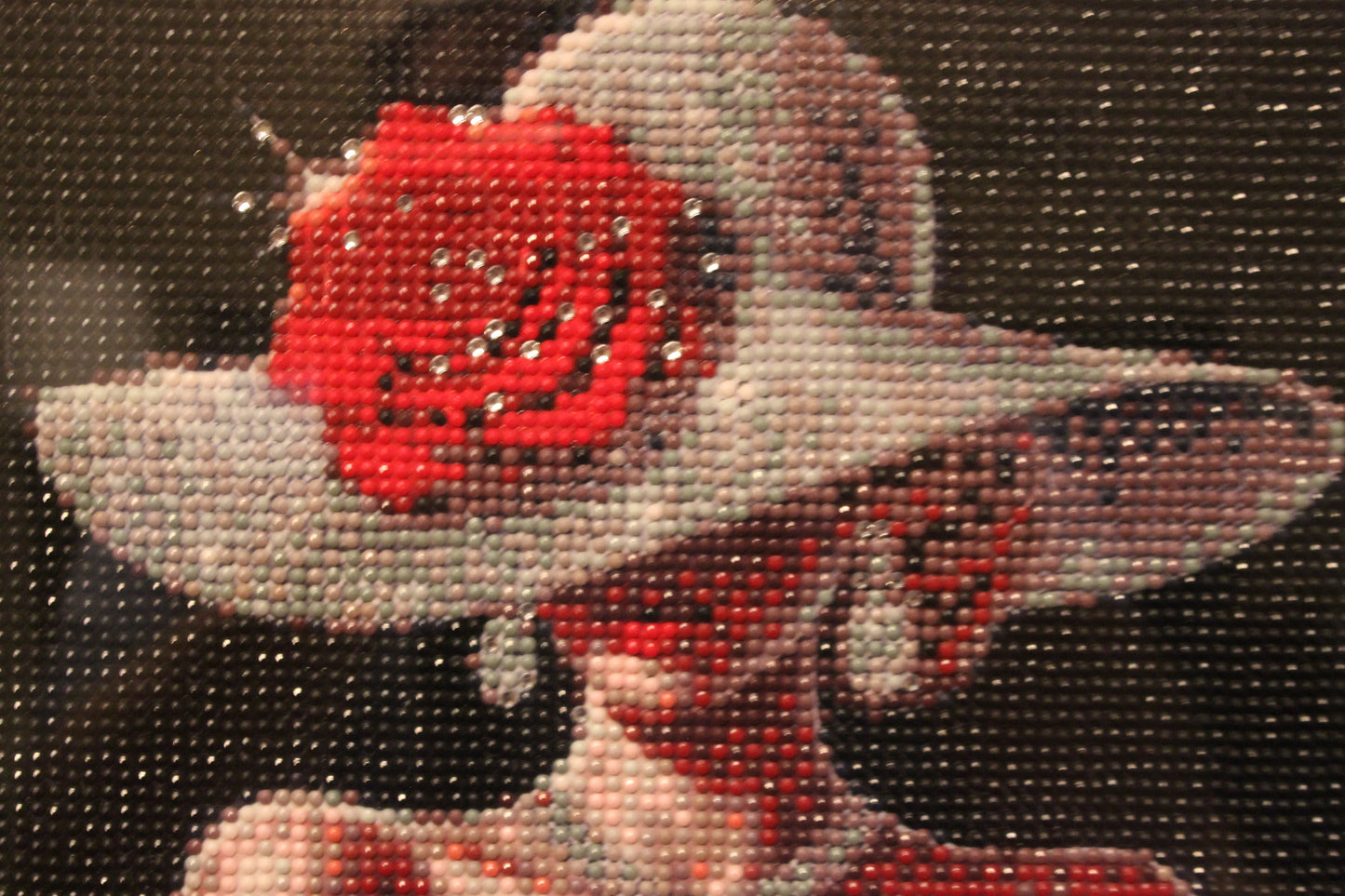 Decorative figure with a red rose on a gray hat against a dark background