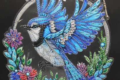 Multi Colored Suncatcher Diamond Art with a Blue Jay among Multi Colored Flowers